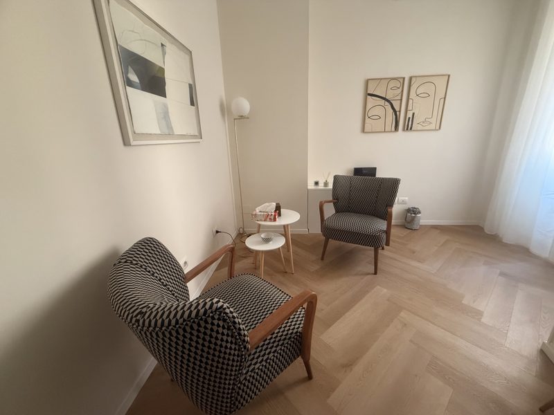 Lo studio in zona Porta Venezia: due poltrone una di fronte all'altra in una stanza luminosa con parquet